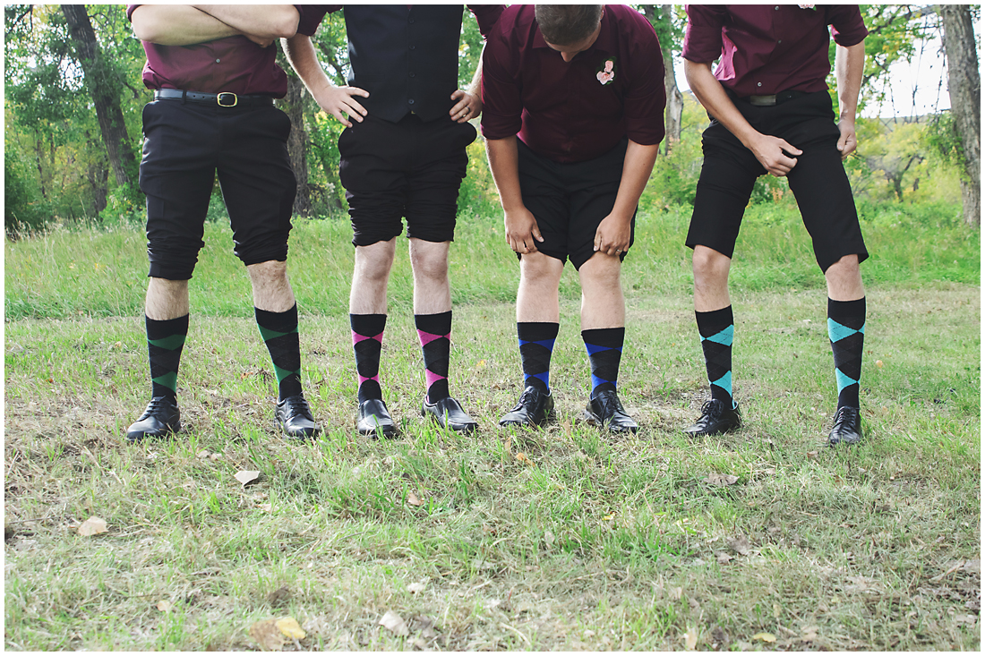 groomsmen with colourful socks A stunning Fall wedding in Lethbridge Alberta - a religious church ceremony at the URC Church with stained glass windows, a quick stop at the Wooden Shoe for lunch and bridal party pictures at Indian battle park. #albertawedding #lethbridge #redwinewedding #redcolourscheme #babiesbreathboquet #indianbattlepark #woodshoe #overcastwedding #fallwedding #kissingcouple #brideandgroom #emotionalwedding #church #churchceremony