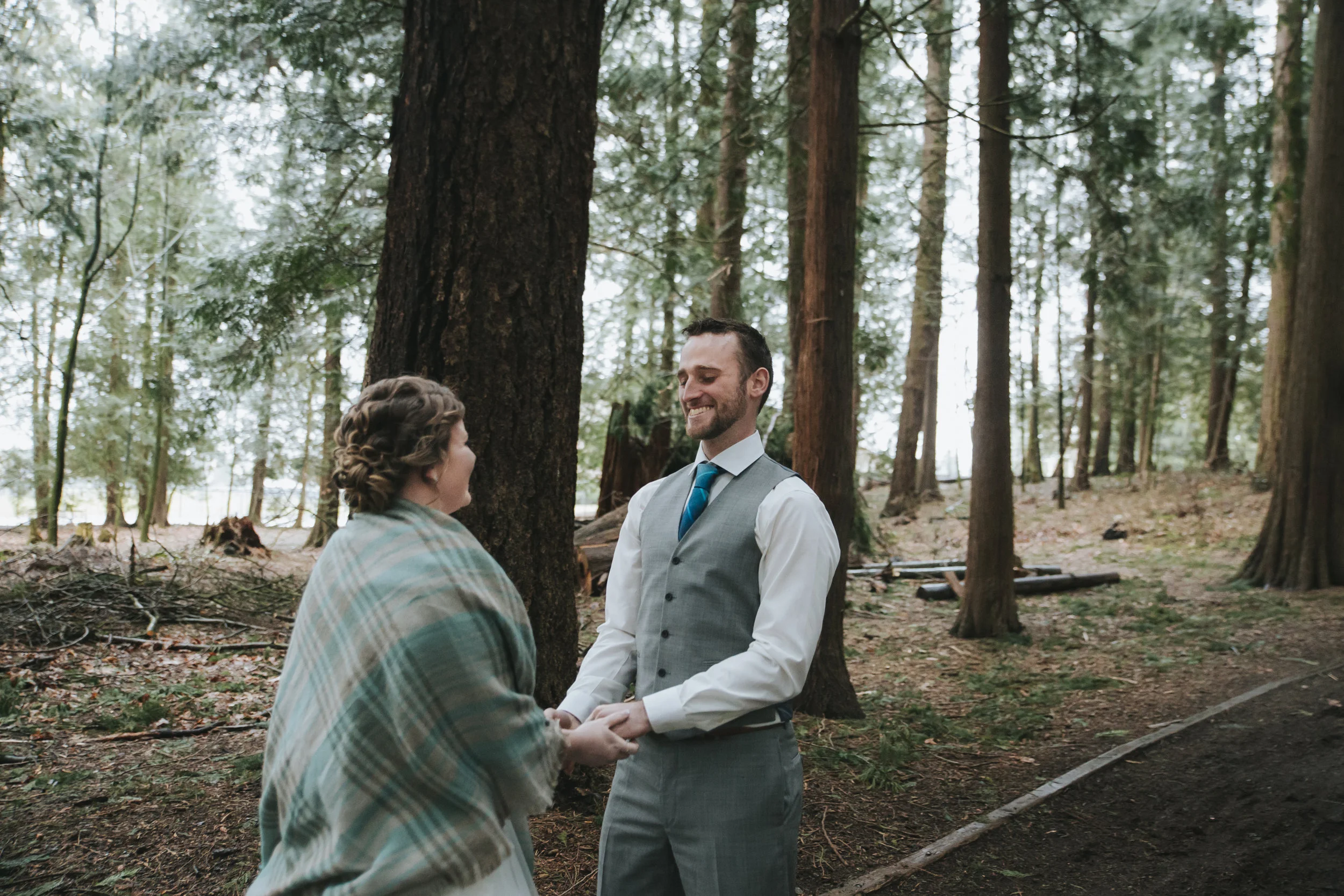 First look A rainy forest wedding in Lynden Washington, featuring teal blue accents, rustic details, umbrellas and a large bridal party.#rain #wedding #lynden #washington #umbrella #spring #teal #grey #brown #trees #romantic #documentarywedding #unposed #romanticposes #couple #largebridalparty Photography by Christina Voorhorst of Mimsical Photography. Do not alter, crop, edit or share these images without proper credit or permission. www.mimsicalphotography.com 
