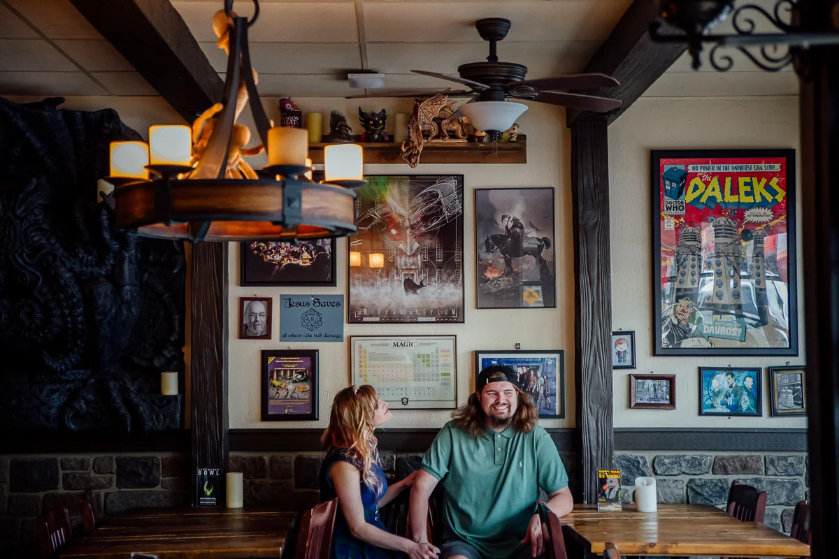 Couple sitting in Storm Crow Tavern. Storm Crow Tavern Documentary Engagement Photography, Nerd Bar, Board Games by Mimsical Photography. Real stories about Real Couples.