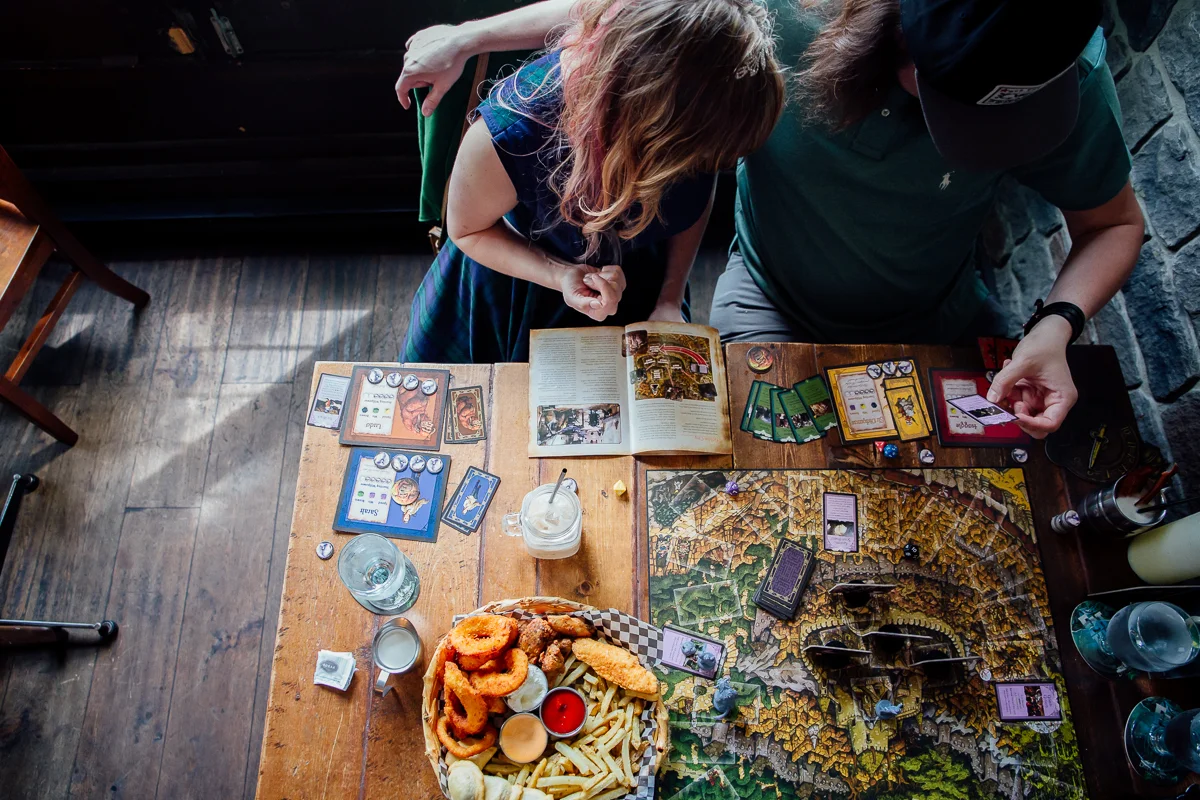 Couple Playing Board Game and sharing lunch. Storm Crow Tavern Documentary Engagement Photography, Nerd Bar, Board Games by Mimsical Photography. Real stories about Real Couples that are just as unique as they are. #unique #vibrant #personality #nerd #princess #ecclectic #gamer #couple #tavern #vancouver #candid #storytelling