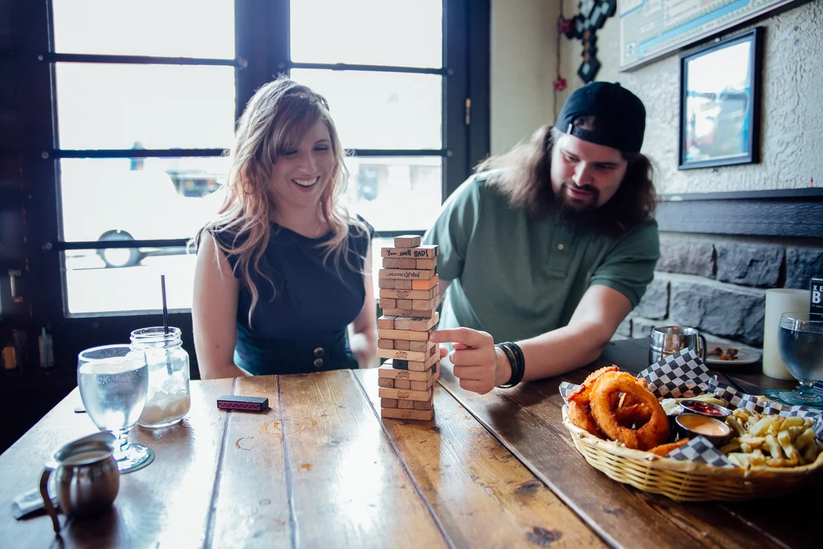 Storm Crow Tavern Jenga game with couple. Storm Crow Tavern Documentary Engagement Photography, Nerd Bar, Board Games by Mimsical Photography. Real stories about Real Couples that are just as unique as they are. #unique #vibrant #personality #nerd #princess #ecclectic #gamer #couple #tavern #vancouver #candid #storytelling