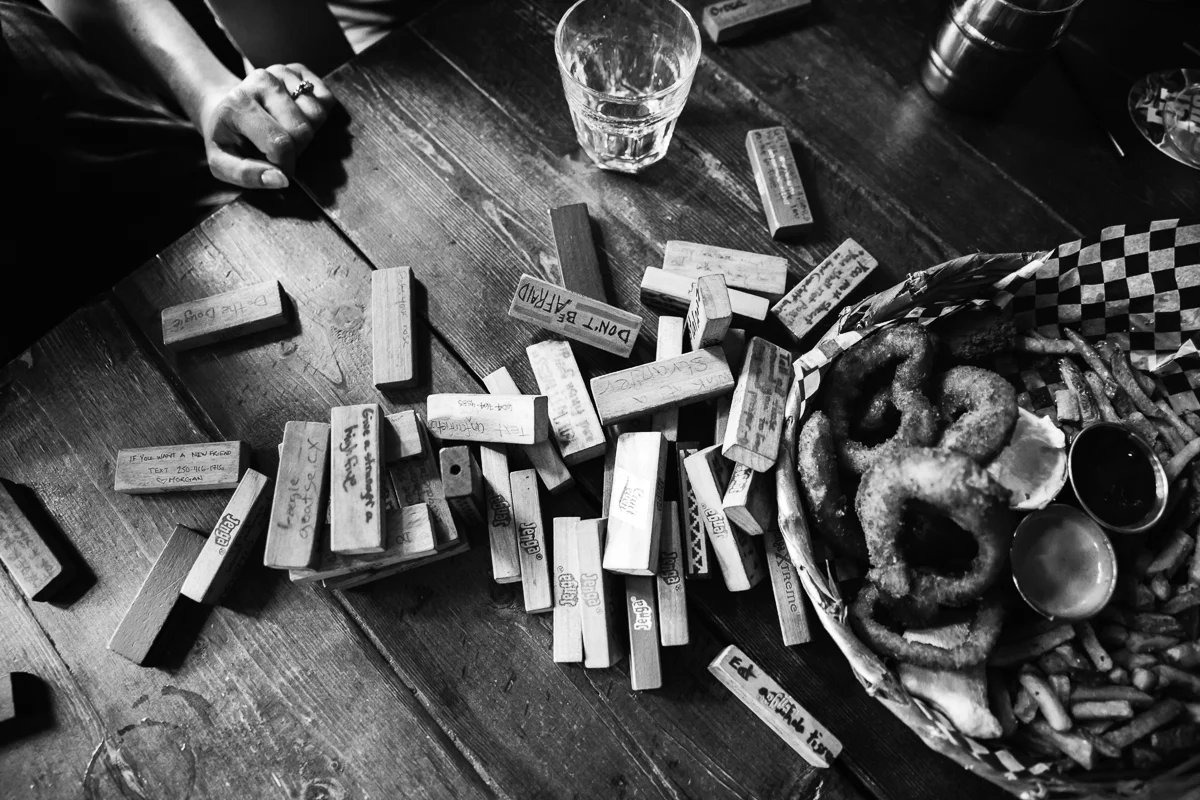 Black and White aftermath of Jenga tower falling over Storm Crow Tavern Documentary Engagement Photography, Nerd Bar, Board Games by Mimsical Photography. Real stories about Real Couples that are just as unique as they are. #unique #vibrant #personality #nerd #princess #ecclectic #gamer #couple #tavern #vancouver #candid #storytelling