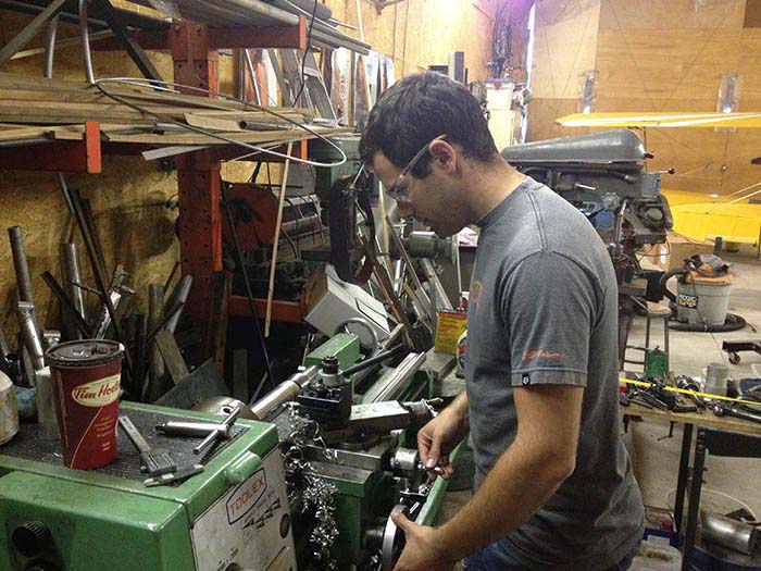 Cameron turns an aluminum part of the Dummy Rotor Axle on the lathe at Cleland Instruments' shop.