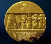 Ancient carved gold artifact with detailed figures in a frieze-like scene