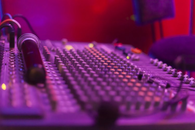 Audio mixing console and microphone illuminated by stage lighting