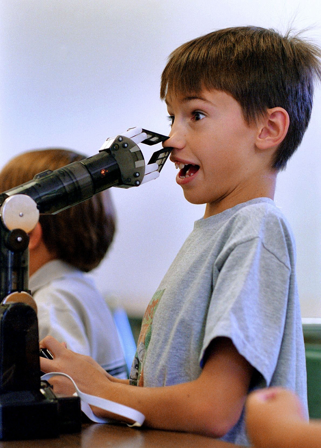  Jason Kaye 9, pinches his nose in the grip of a mechanical robotic arm at the R.G. Smith Clubhouse in Folsom on Thursday July 25, 2002. "Mad Scientist" Jason Turner put on a science class themed "Machine Mania" and featured simple machines. 