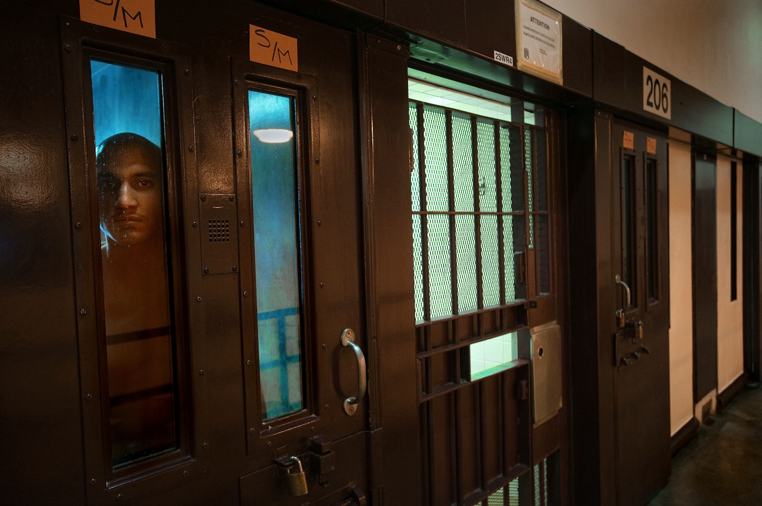 Prison inmate Joell Polanco, at left, peers from his cell in the behavior management unit at the Substance Abuse Treatment Facility in Corcoran on Thursday, March 25, 2010.