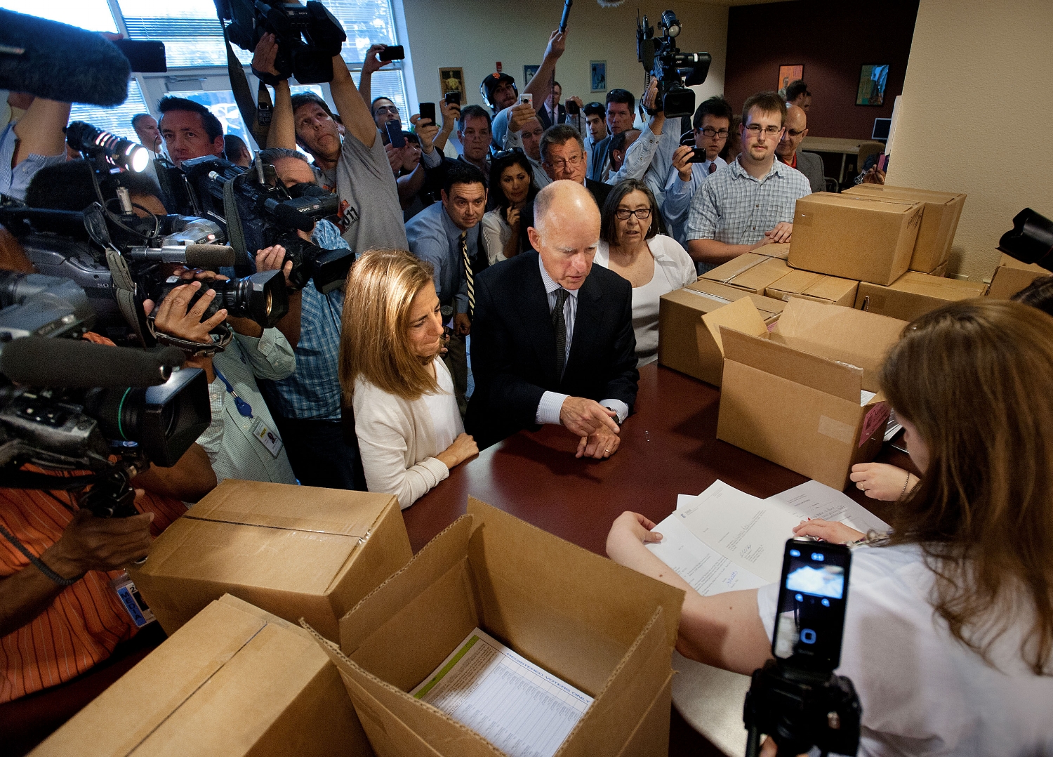 California Governor Jerry Brown delivers signatures for a tax measure to the county registrar's office in Sacramento on Thursday, May 10, 2012. HIs wife, First Lady Anne Gust Brown is with him on the left.