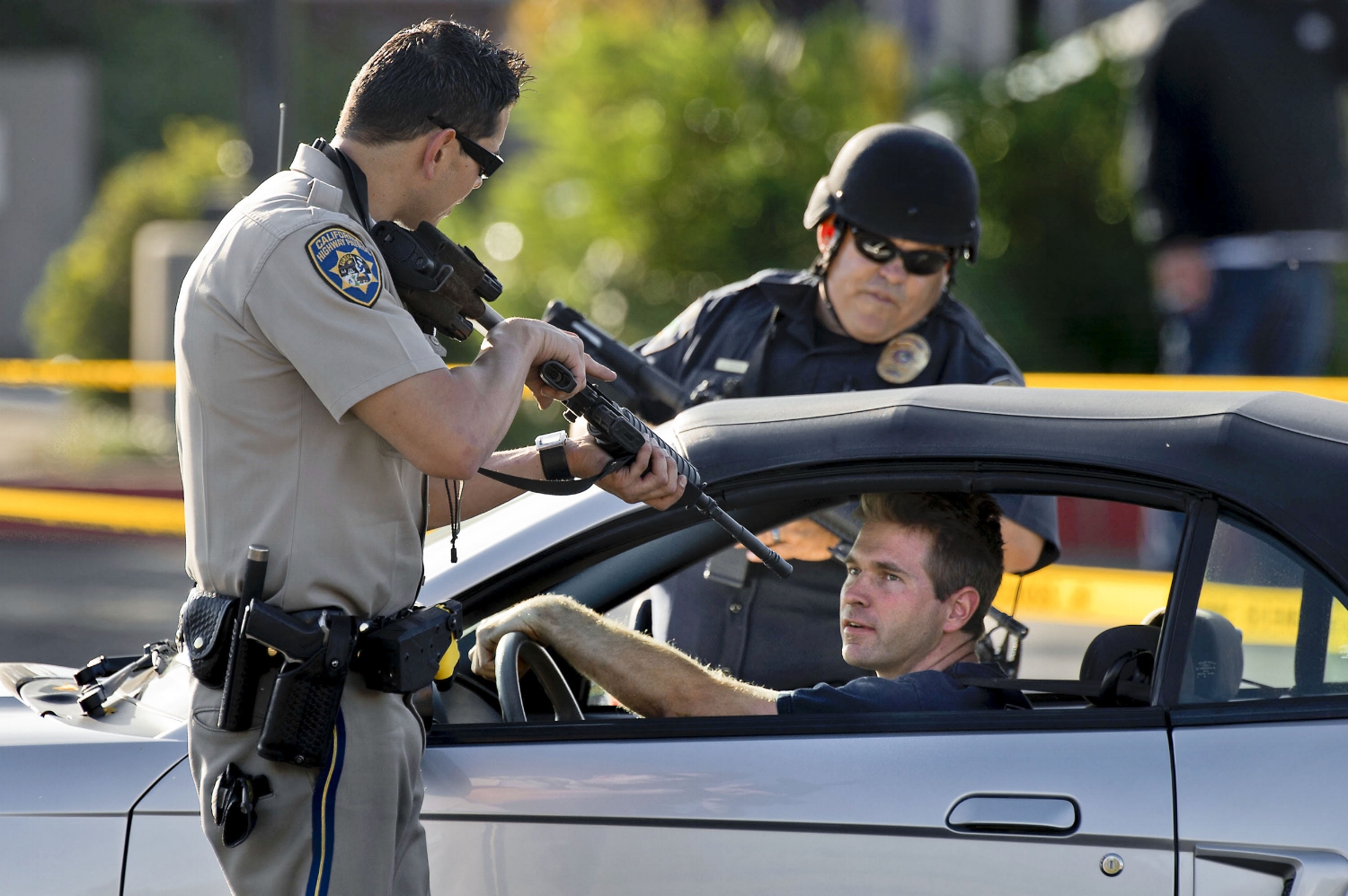  A California Highway Patrol officer and Roseville Police stop a motorist as he leaves a neighborhood where a search continues for a man suspected of shooting an Immigration and Customs Enforcement officer in Roseville on Friday, October 25, 2013. In