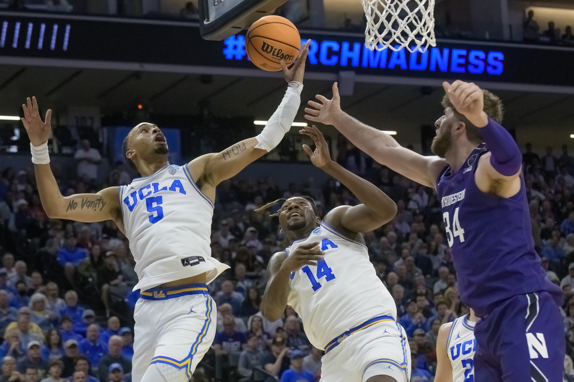  UCLA guard Amari Bailey (5) and forward Kenneth Nwuba (14) battle for a rebound with Northwestern center Matthew Nicholson during the first half of a second-round college basketball game in the NCAA Tournament in Sacramento, Calif., Saturday, March 
