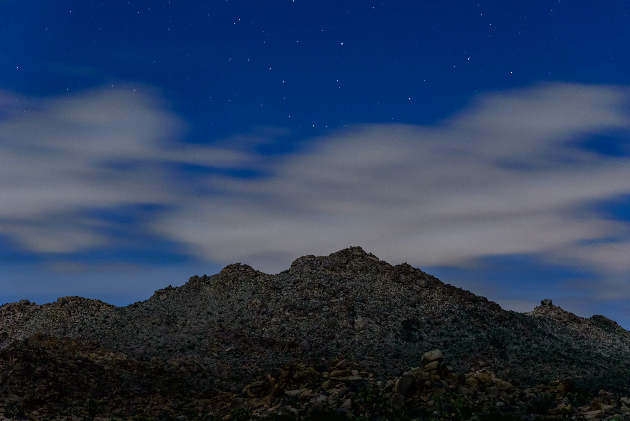 Moonlight dances between revealing and hiding layers of earth. Joshua Tree National Park, CA.