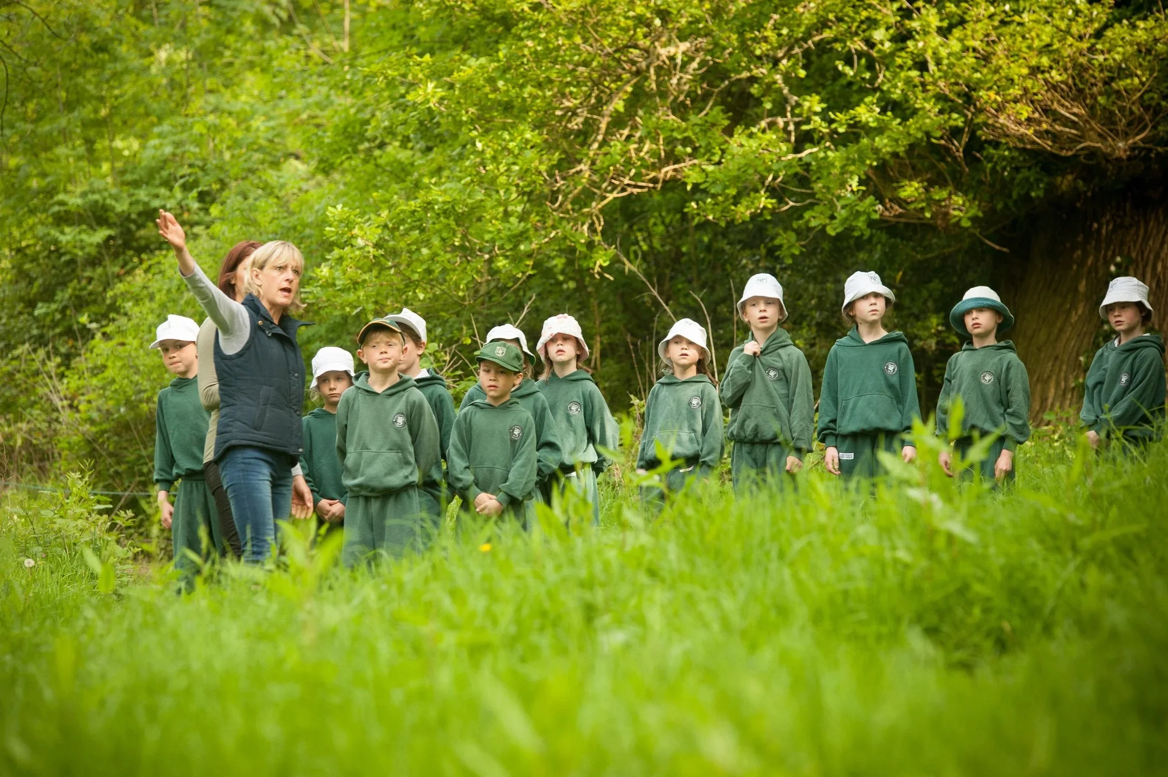 A bright lifestyle photograph for a preparatory school prospectus, capturing young pupils in outdoor jackets eagerly exploring nature and learning together during an educational field trip.