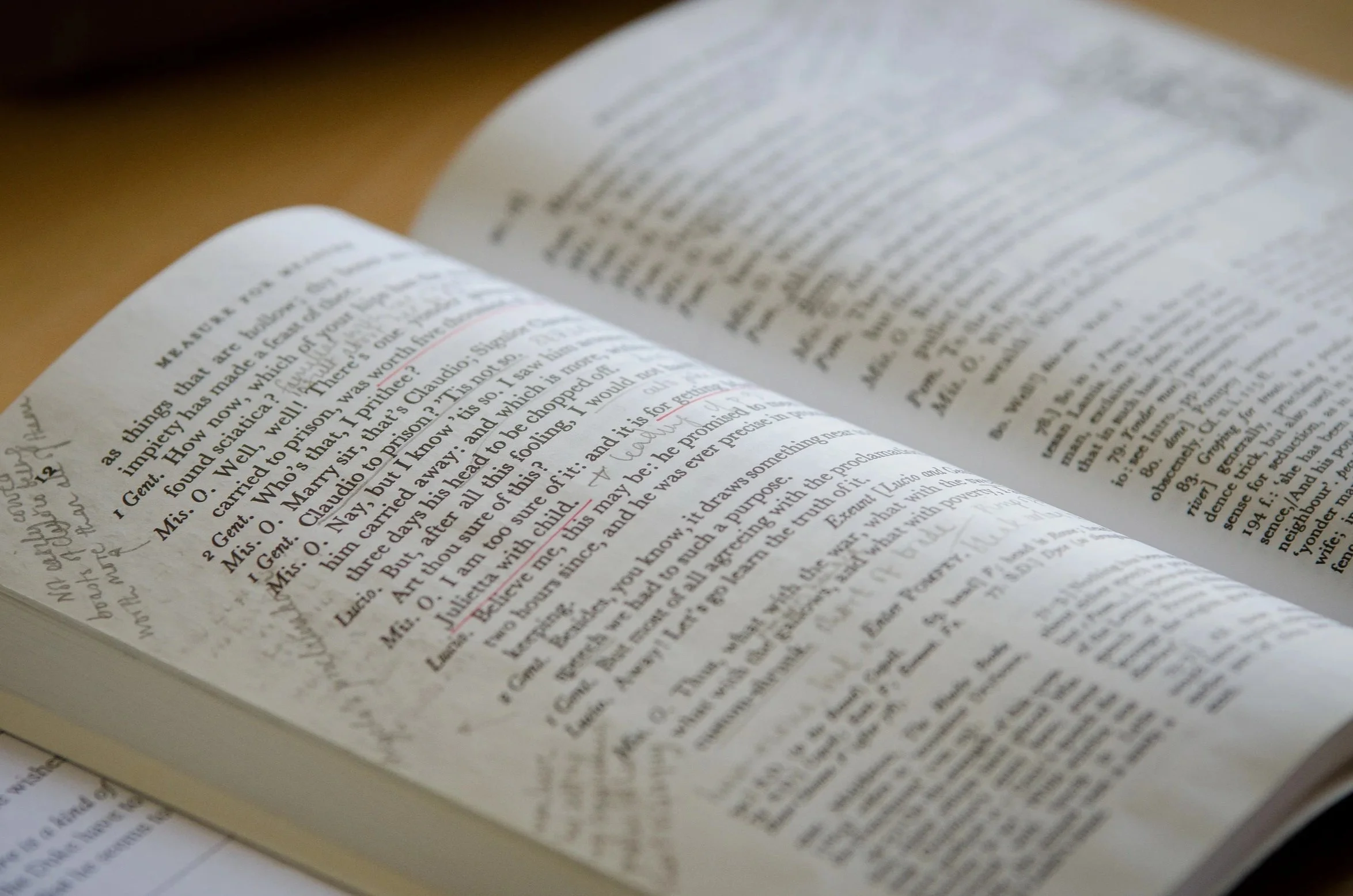 A macro photograph of the printed text and pages of an open academic book on a classroom desk.