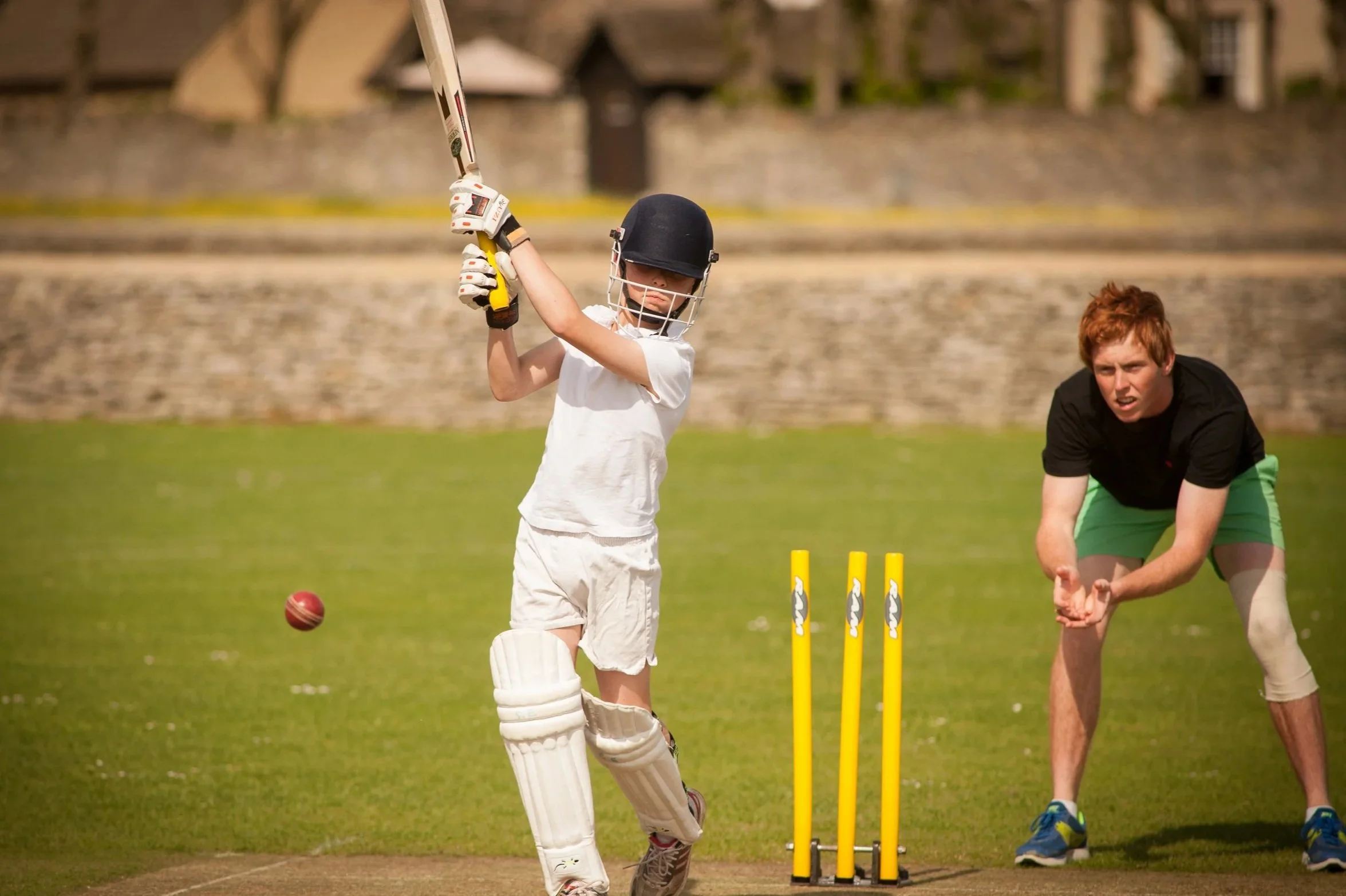 Editorial prep school PR photography showing a junior school pupil playing cricket, showcasing traditional sports programs and competitive team games at a premium independent school.