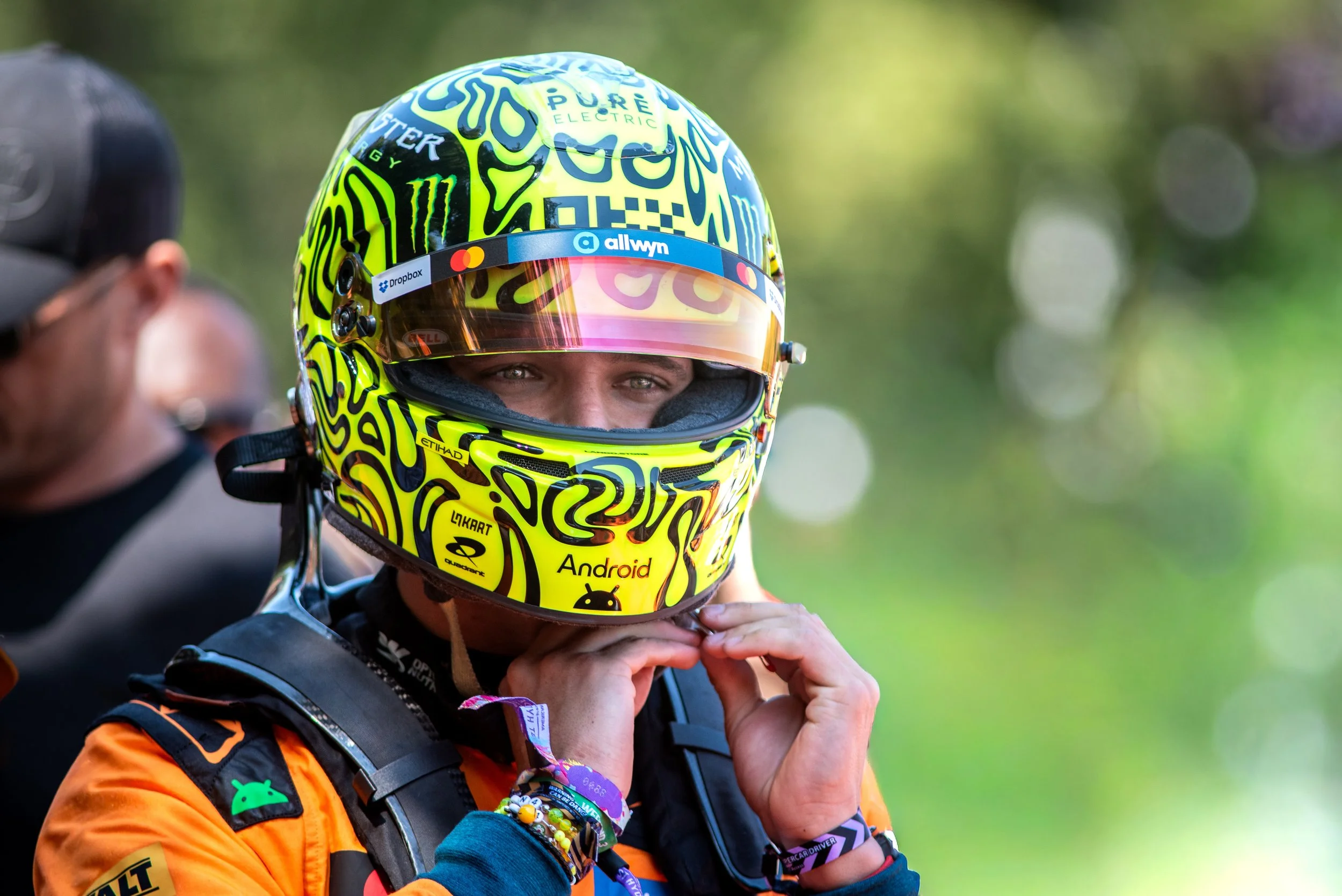 Close-up shot of Lando Norris securing his racing helmet in the McLaren paddock at the 2026 Goodwood Festival of Speed.