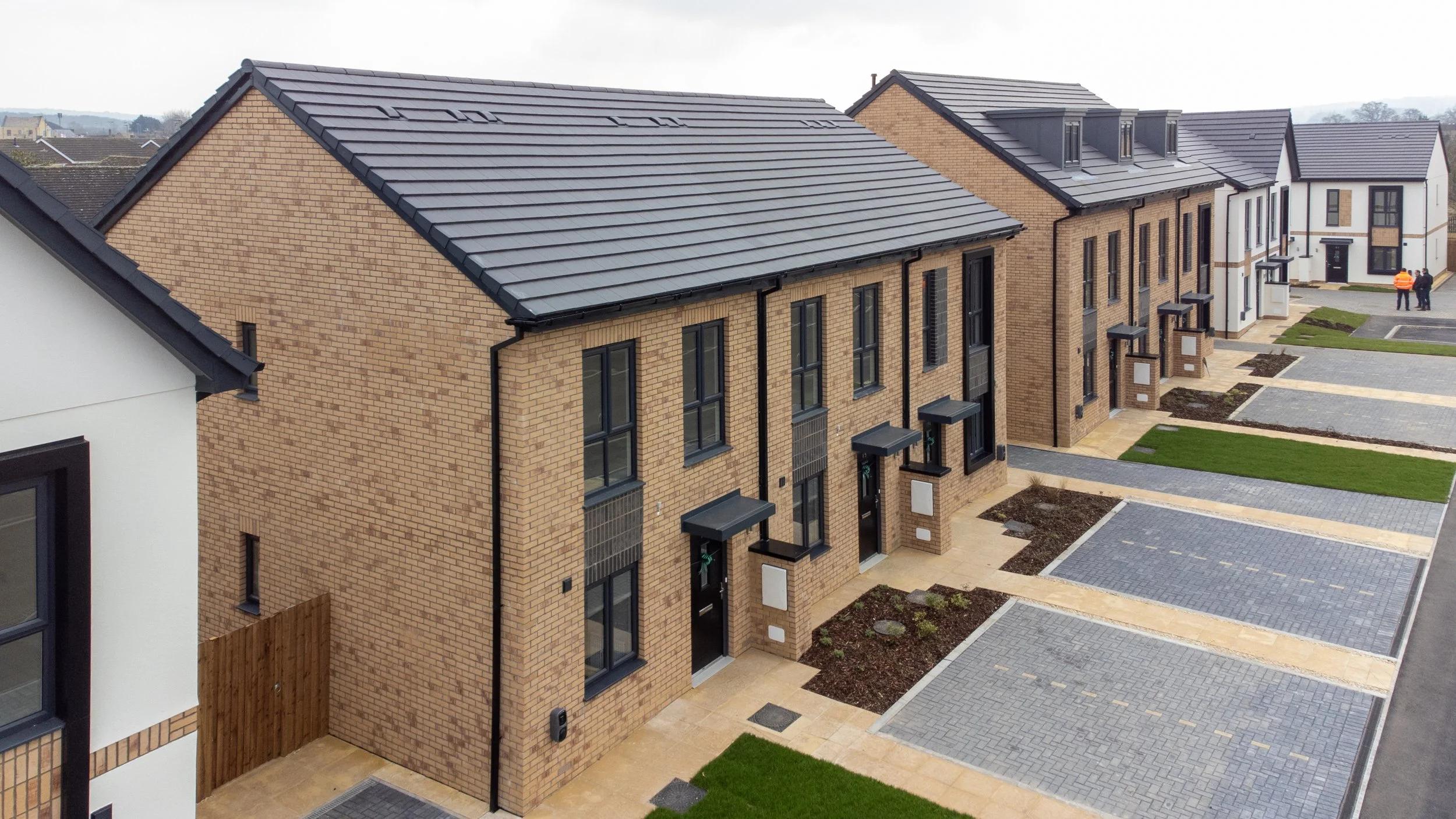 An elevated aerial view of a clean, modern row of newly built residential homes, highlighting the uniform architectural style and organized layout of the development.