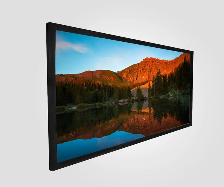 A flat-screen TV displaying a scenic landscape of mountains, trees, and a body of water at sunset.