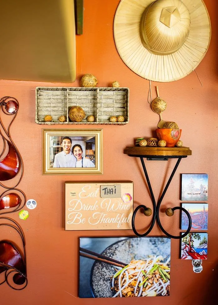 A terracotta wall inside Barn Nork with a framed photo of the chefs and a Thai sun hat