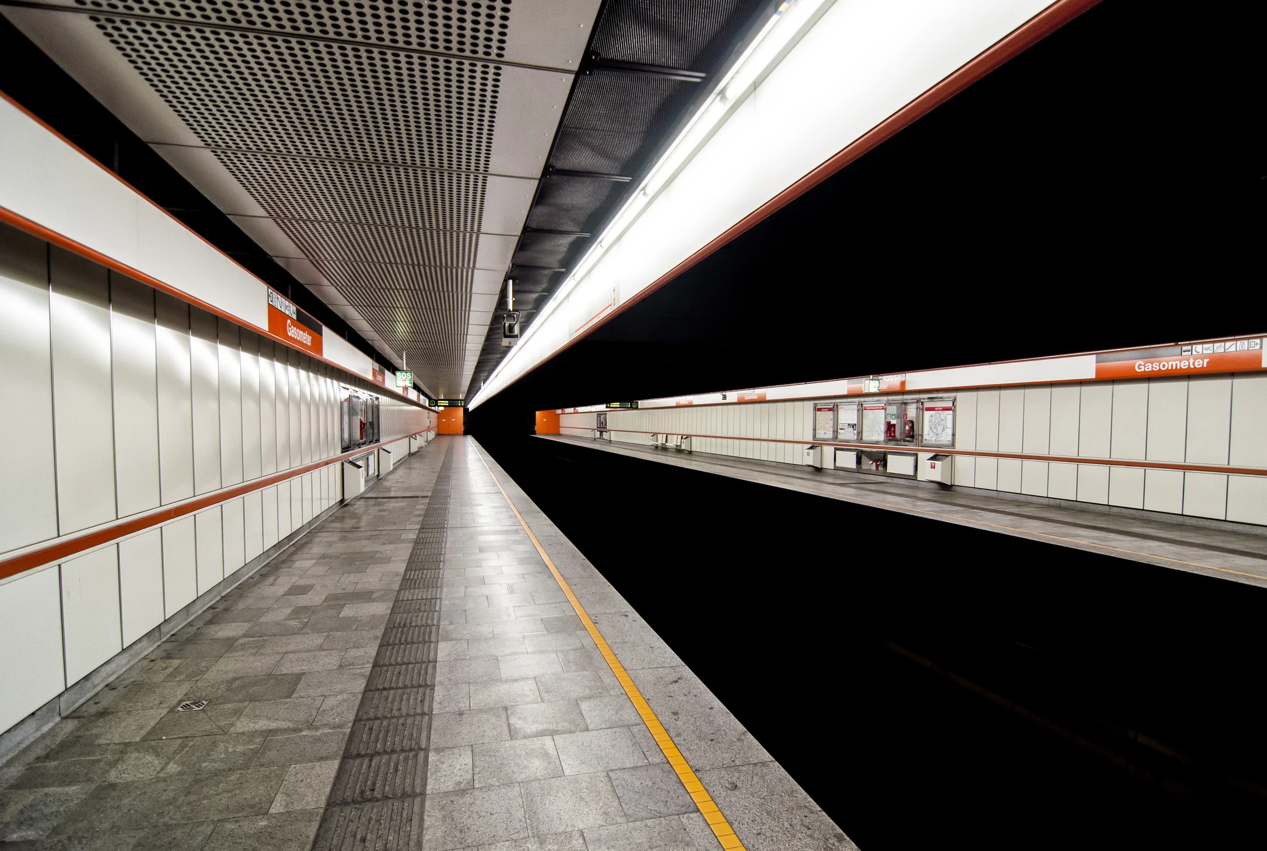 Leerer U-Bahnhof mit dunkelgerben Signalen und Markierungen, abgeschiedene Gleise, keine Züge, moderne Station