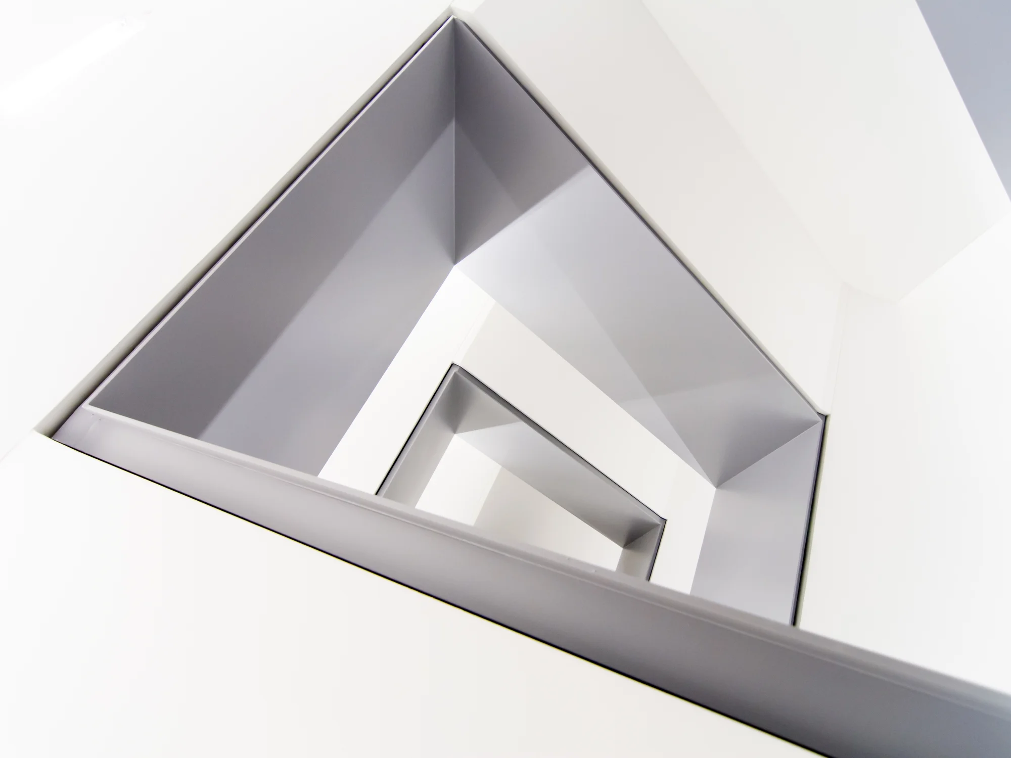 Innenansicht eines modernen Spiegels in einer weißen Wand, Blick von unten nach oben, geometrische Linien und klare Linienführung