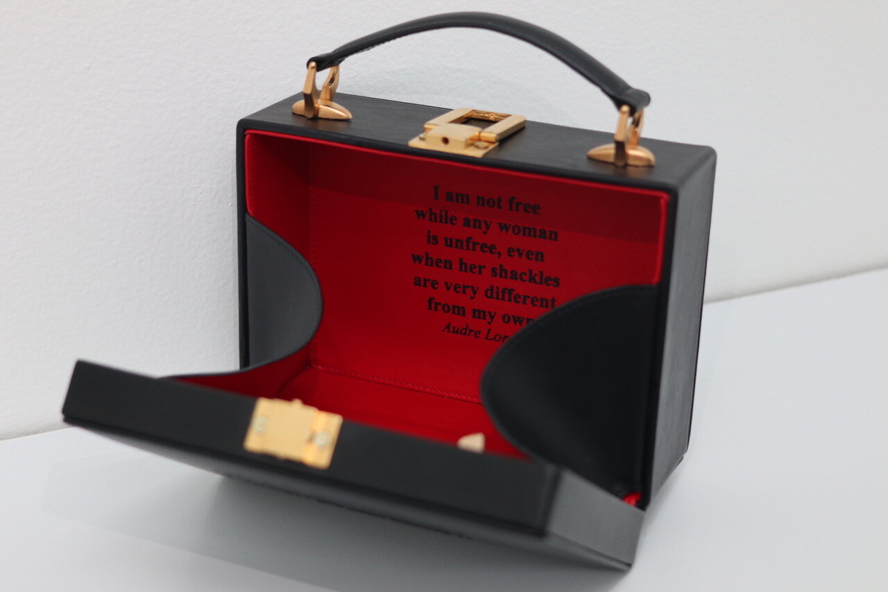  Jaye Moon  I am not free while any woman is unfree, even when her shackles are very different from my own. - Audre Lorde  2020  Custom made leather handbag with embossed exterior, red leather lining, mirror and brass,  6 x 8 x 4 inches  Edition of 2
