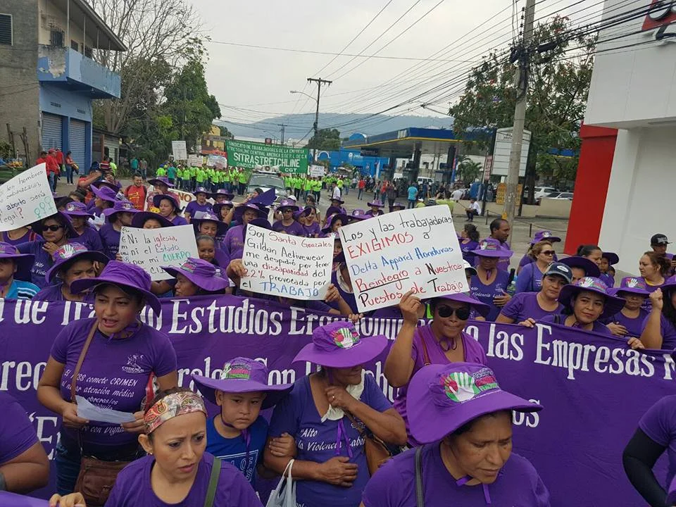 May Day March 2017. Paper sign to the right reads “Male and female workers demand that Delta Apparel Honduras give us our jobs back.” Photo credit: CODEMUH