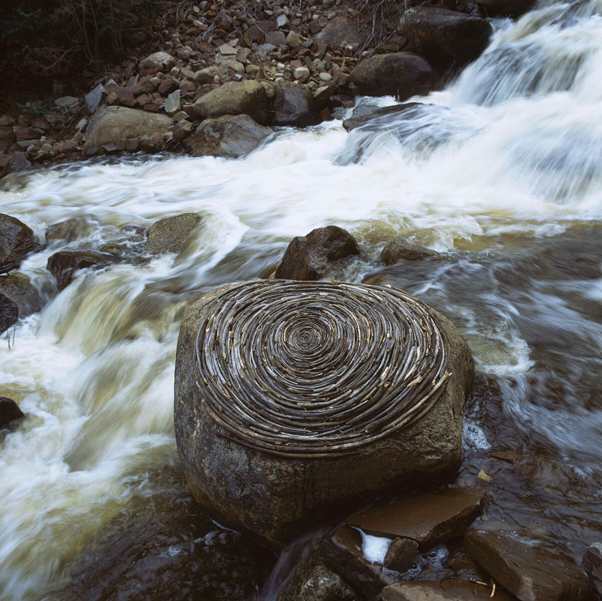 andy-goldsworthy-reworked-sticks-on-river-boulder.jpg