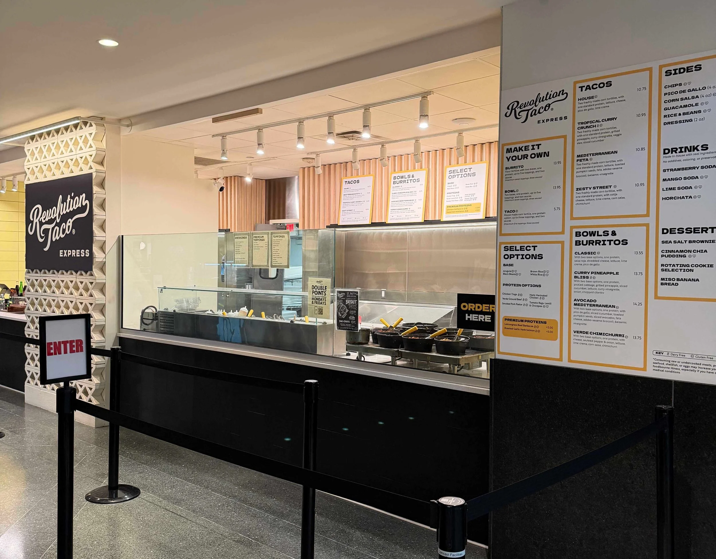 Interior view of Revolution Taco Express counter at Comcast Center in Philadelphia with menu boards, ordering station, and queue barriers