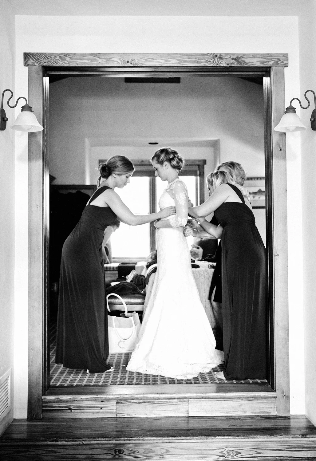 Bridesmaids helping bride into her dress