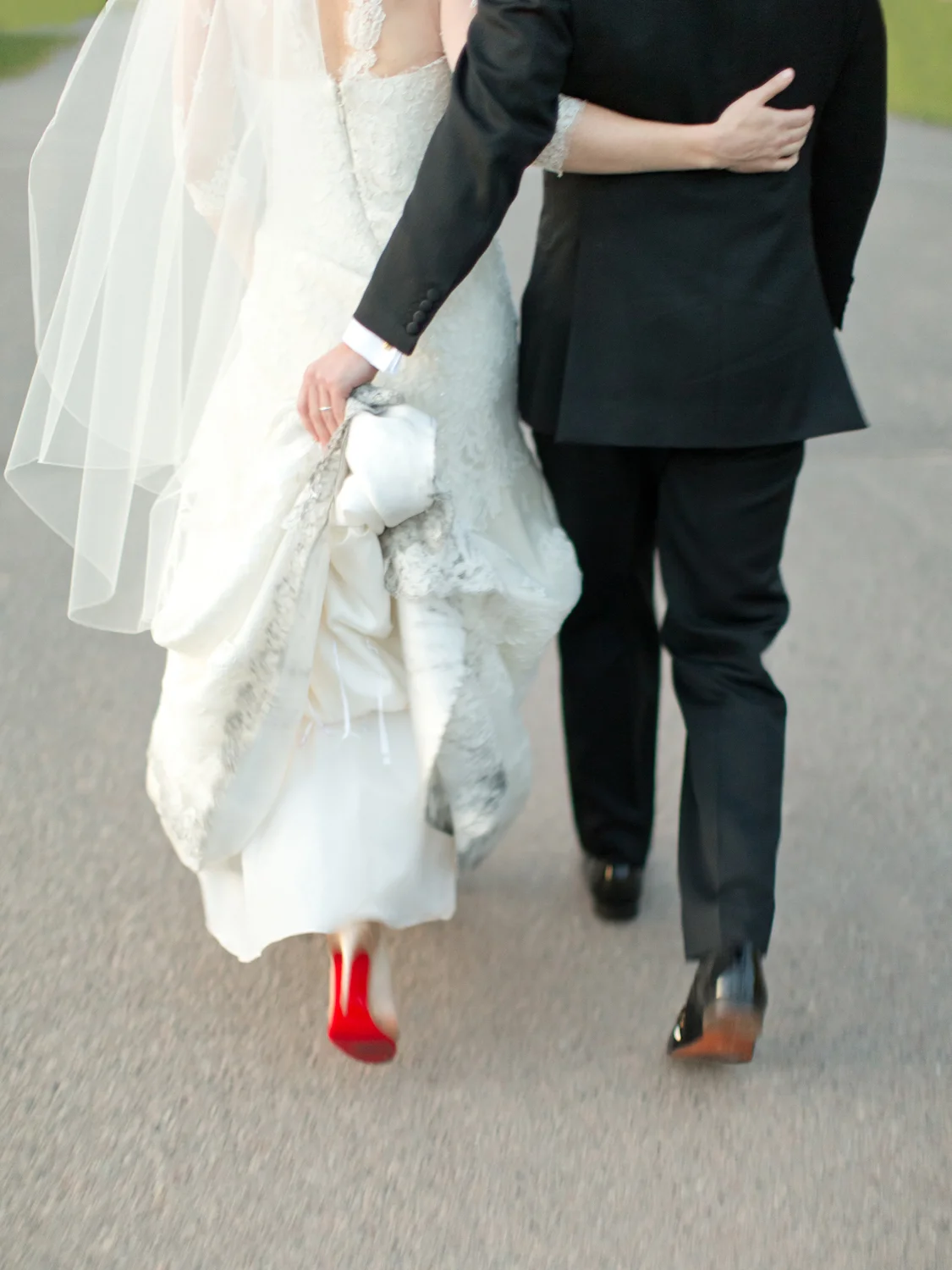 Bride and groom walking with groom holding dress train