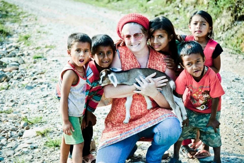 While taking a walk in a Nepalese village , some kids flocked around me. One of them gave me his pet goat. It made me happy. 