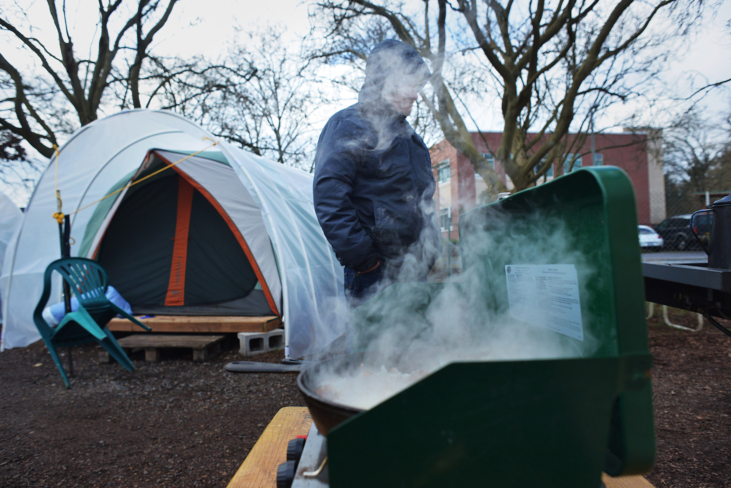 Eugene, Ore. - A transient resident of the Nightingale Health Sanctuary is hidden by steam from a pan of hash browns being cooked for a community breakfast. By: Debra Josephson