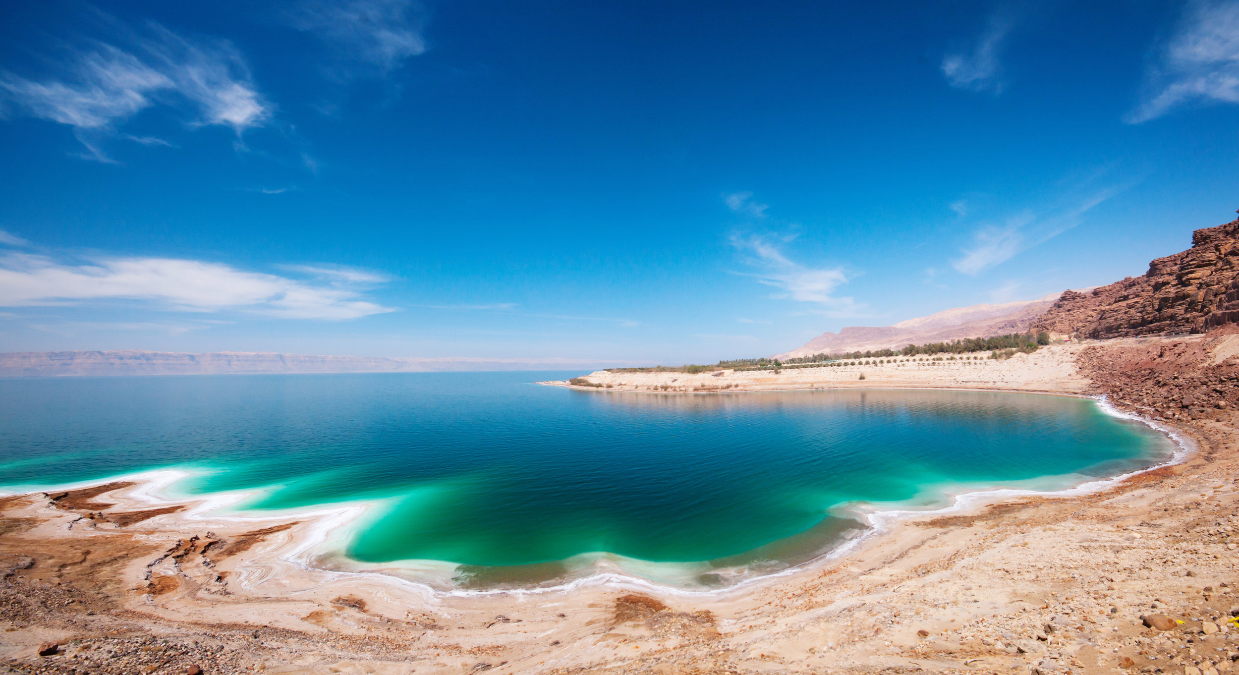 A-beach-by-the-Dead-Sea-with-blue-skies-and-turquoise-water-172401875_4277x2330.jpeg