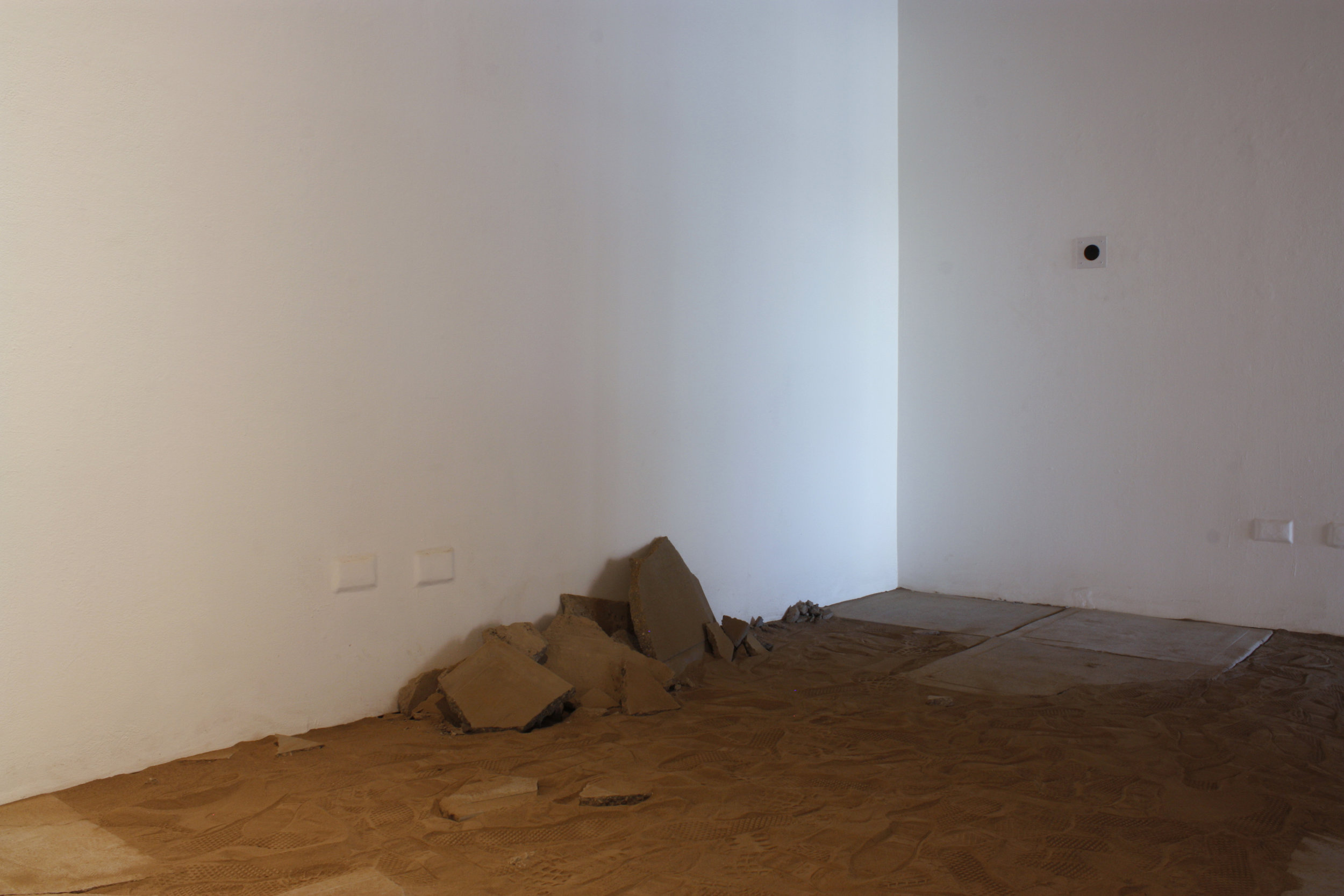   towards a surface  (after entry)   Sifted earth dug from a 5'2" x 2' x 1' area, recording emitted from a speaker, concrete, steel, saliva, and light   16'5" x 7' x 14'  2017 