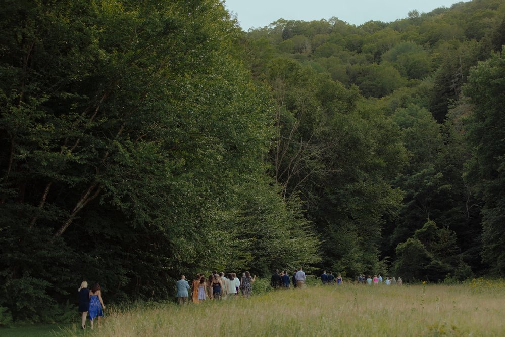 017_cameron-alexa-wedding-89_wedding guests walk through field to wedding ceremony site.jpg