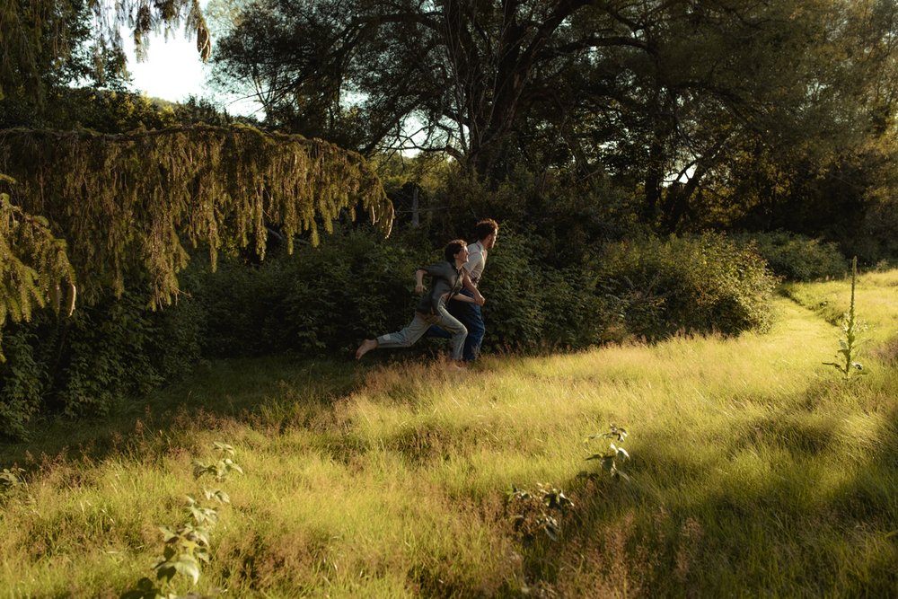26_young playful couple running barefoot through the tall grass at golden hour vermont .jpg