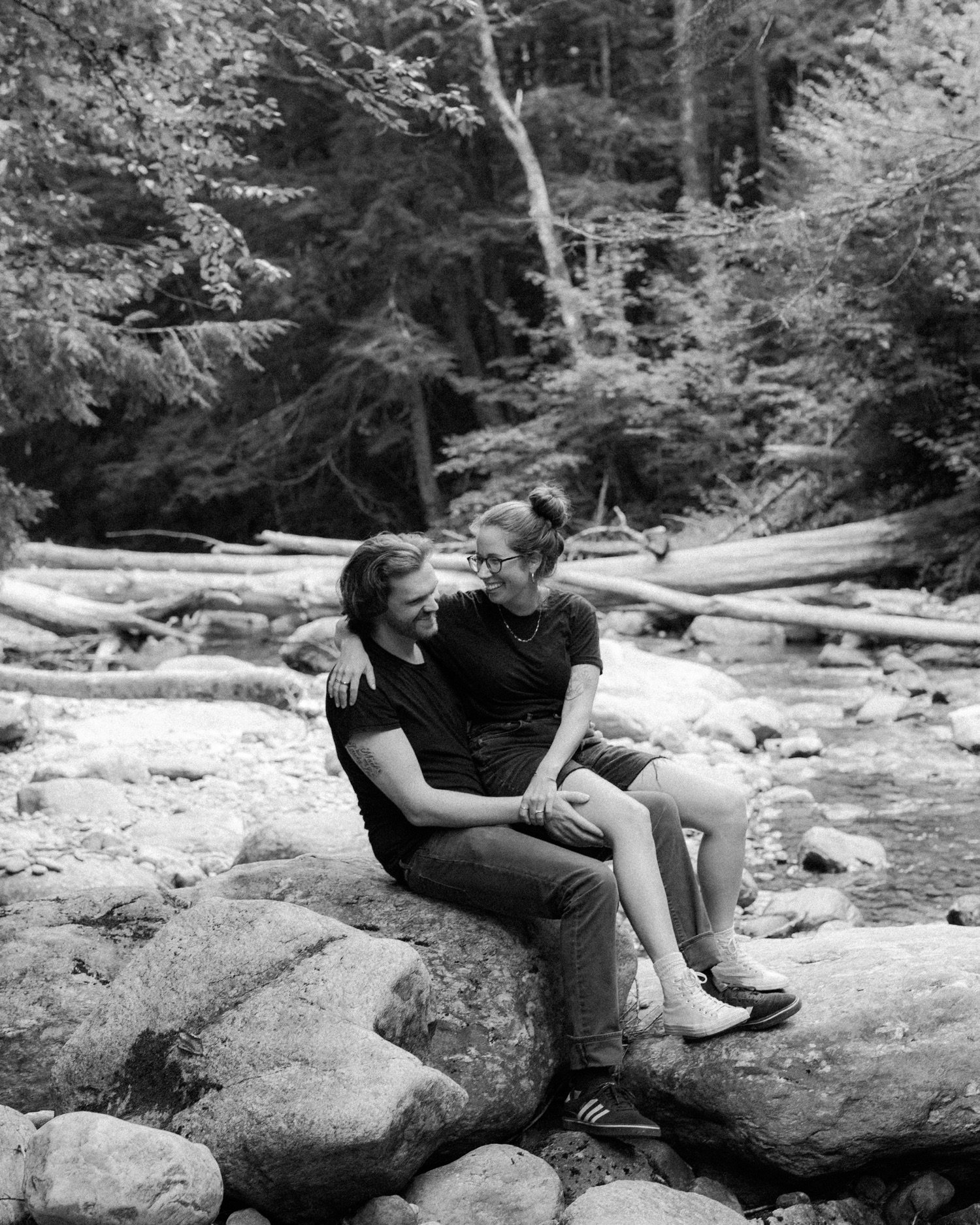 32_couple sitting on lap on rocks by the river at texas falls in hancock vermont .jpg