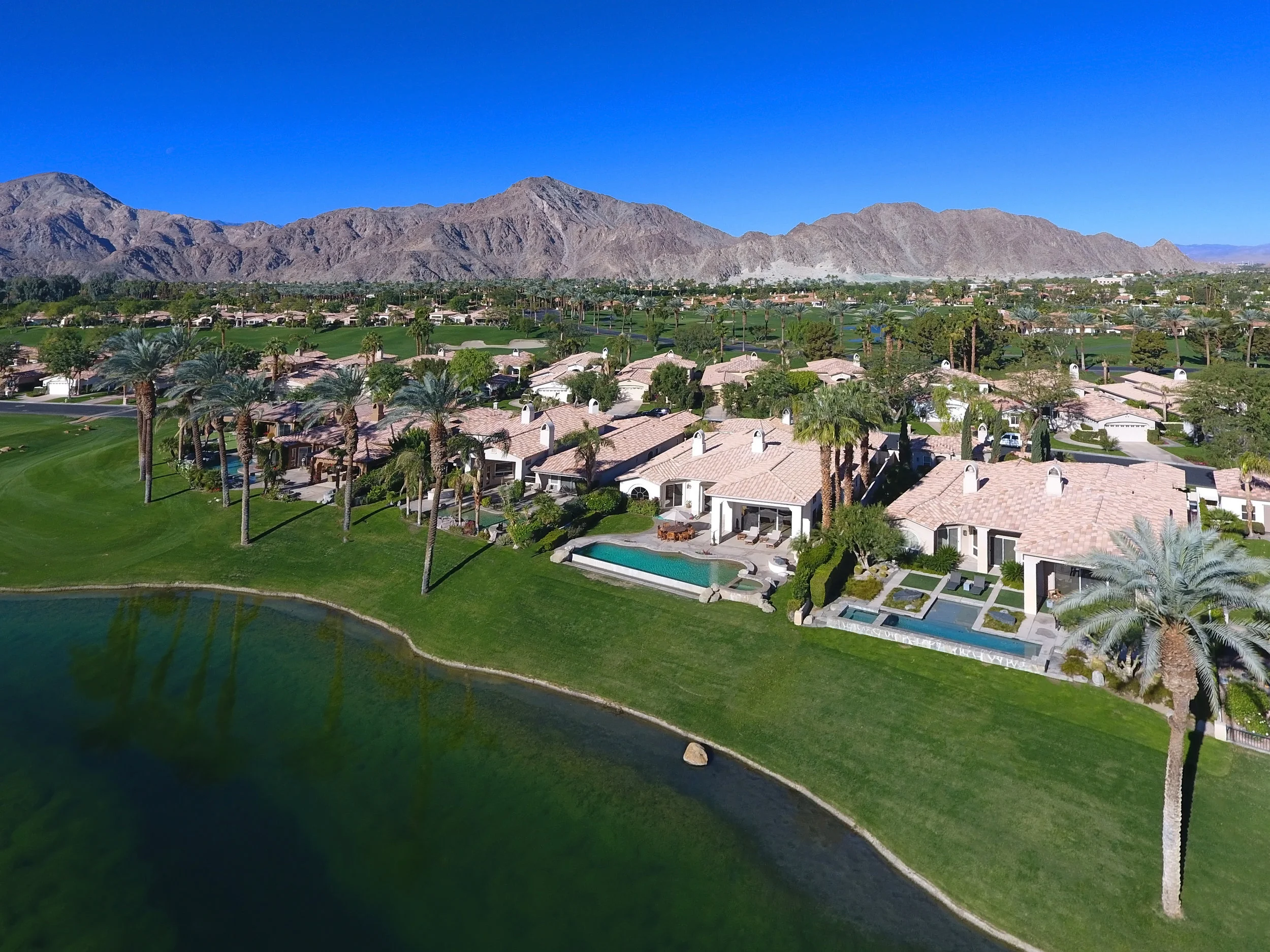 OVER LAKE TO HOUSE AND MOUNTAINS DRONE.jpg