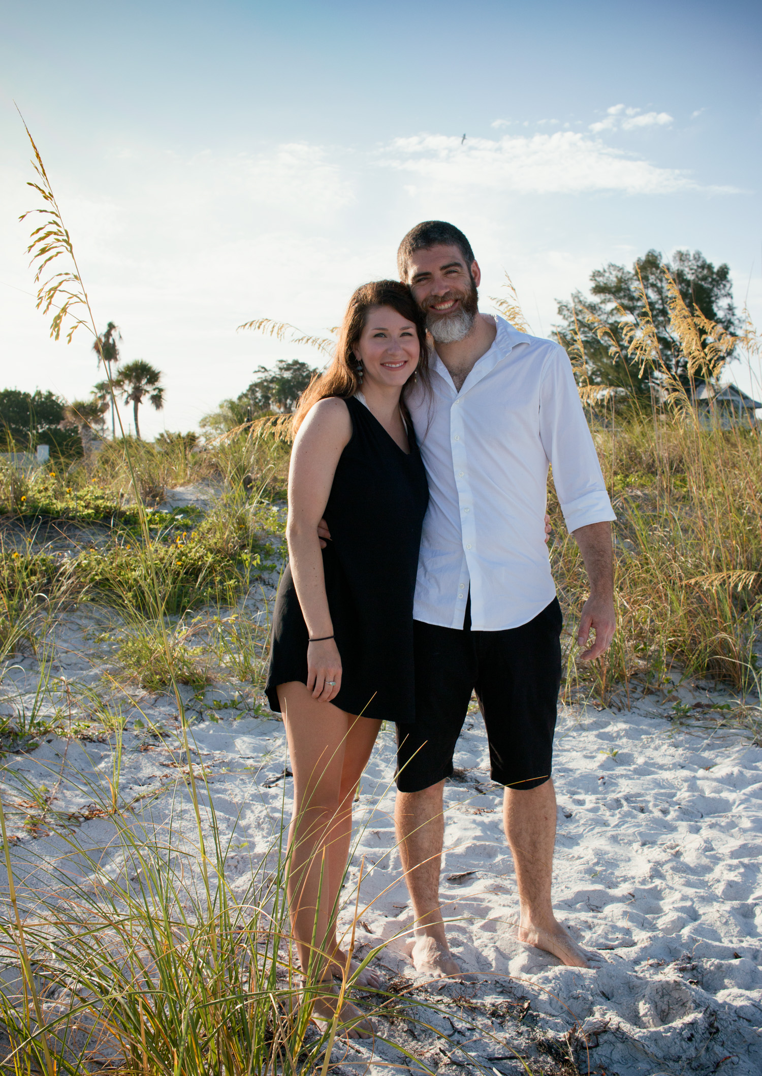 A cute couple pose amongst the white sand and grass at Pass-a-Grille Beach.