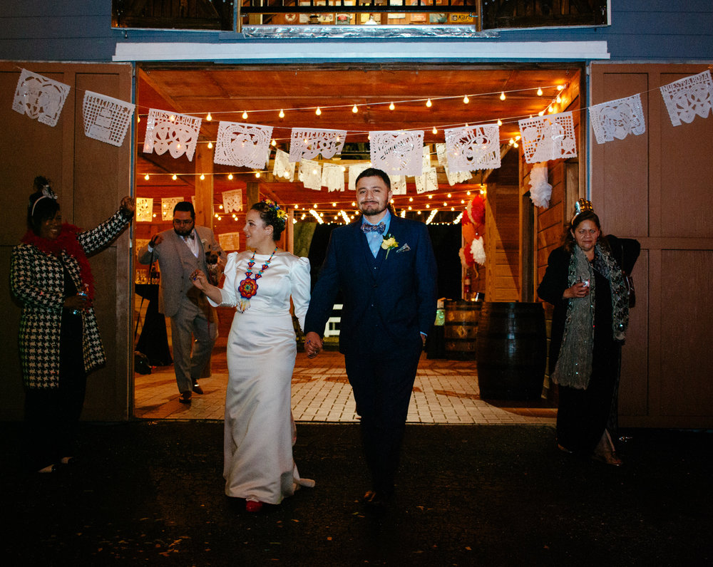 Bride and groom exit the brightly lit venue with joyous smiles.