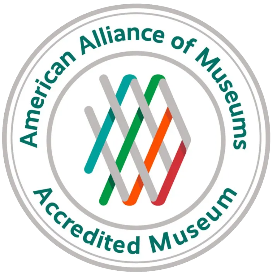 Circular white logo outlined in gray with text "American Alliance of Museums Accredited Museum" in outer ring, and AAM logo in center.