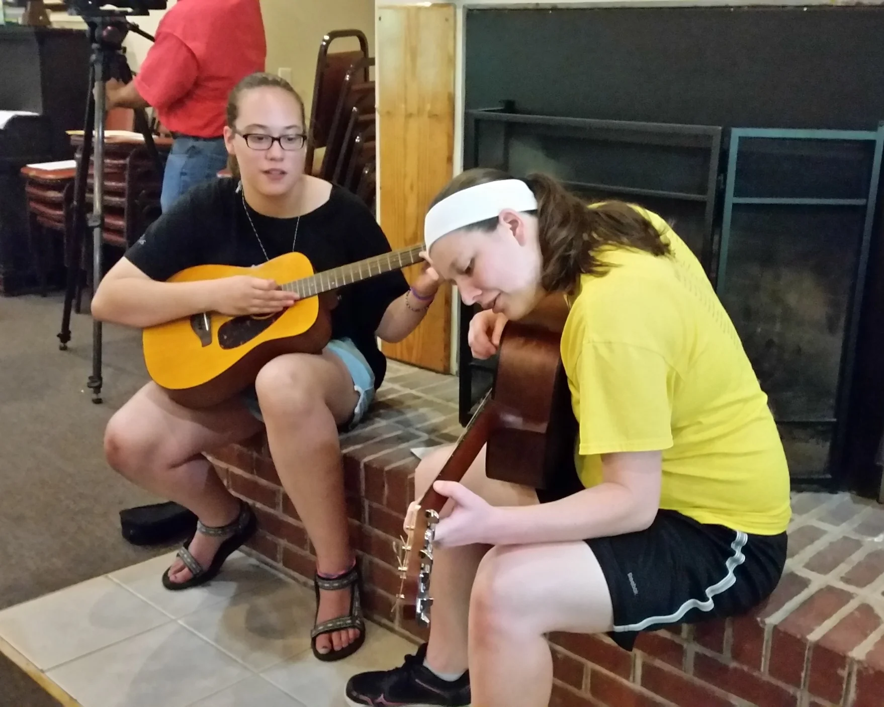 Whitley (right) demonstrates chords to a Youth Folk camper.