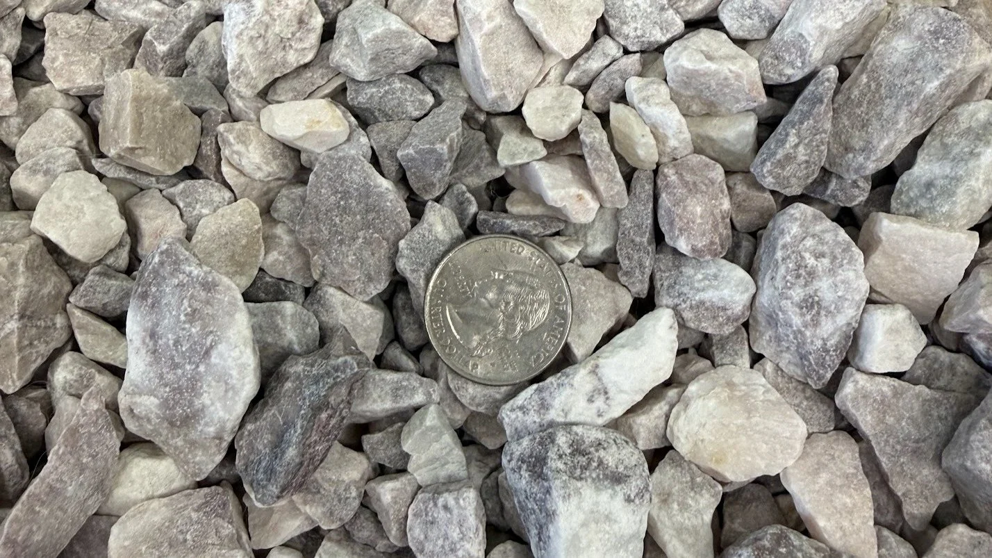 Close-up of small gray and white rocks with a U.S. quarter coin for size reference.