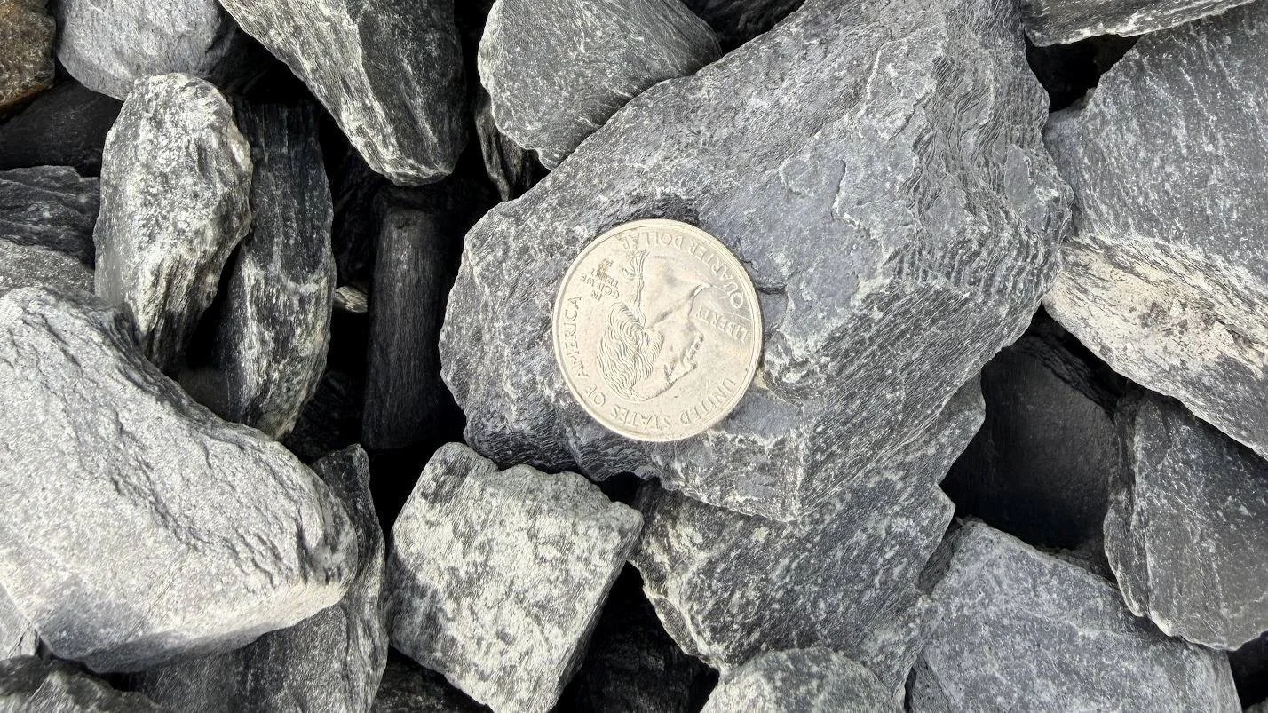 A pile of gray rocks with a British pound coin placed on top of one rock.