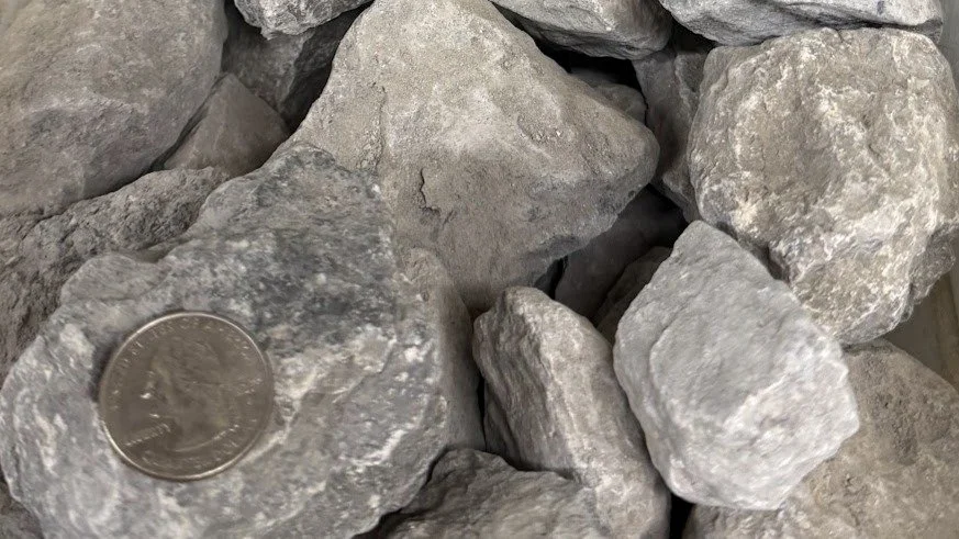 A close-up of several gray rocks with a U.S. quarter coin for size reference.