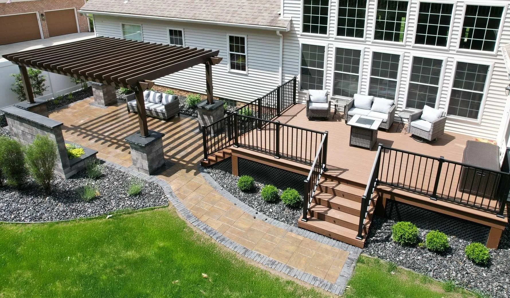 A backyard with a multi-level deck, outdoor seating, a pergola, landscaped garden beds, and a well-maintained lawn.