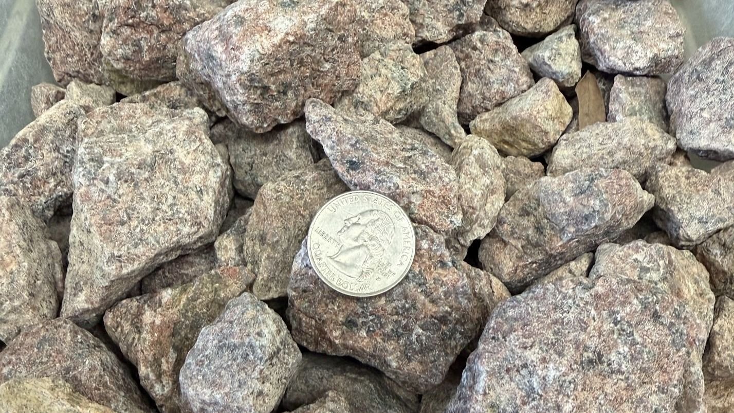 A pile of roughly chopped rocks and a quarter coin for size comparison.