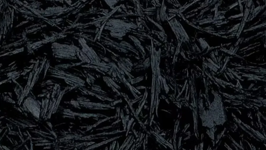 Close-up of dark, textured wood chips or shredded wood material.