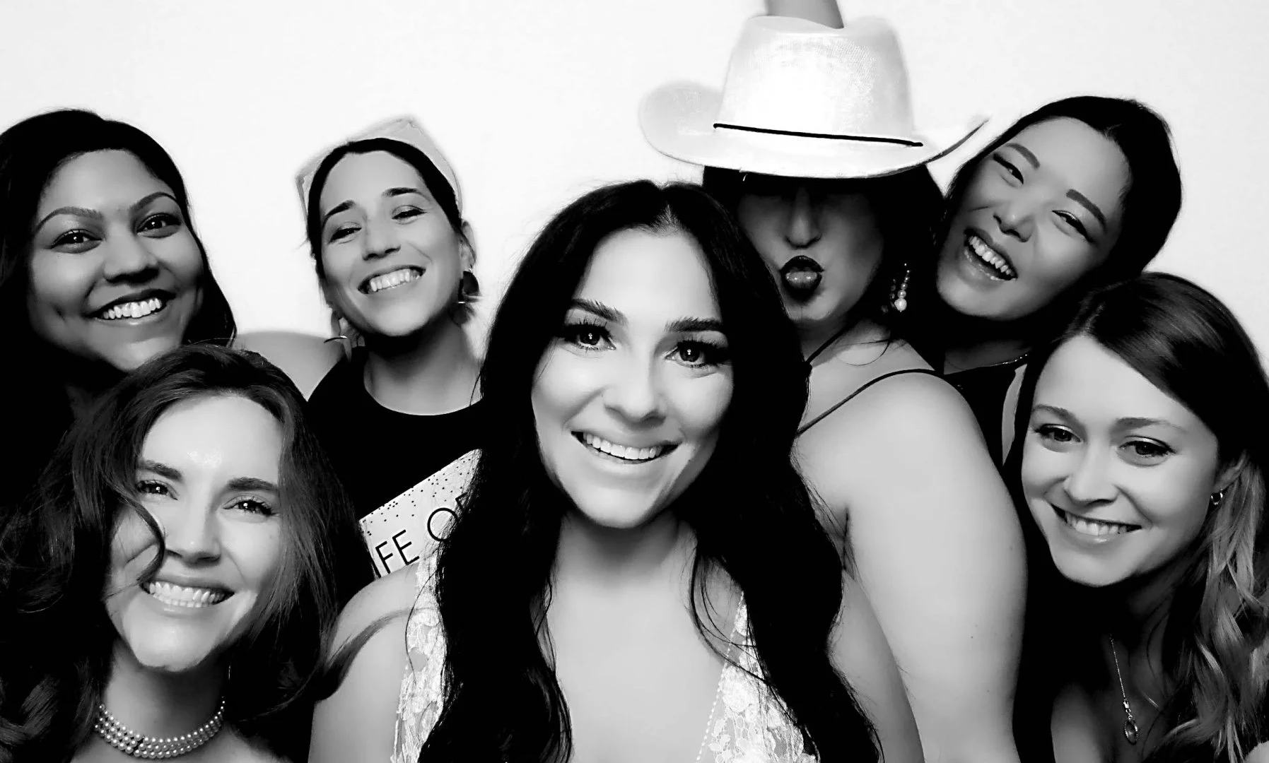 Wedding guests smiling in a black-and-white Glam photo booth portrait.