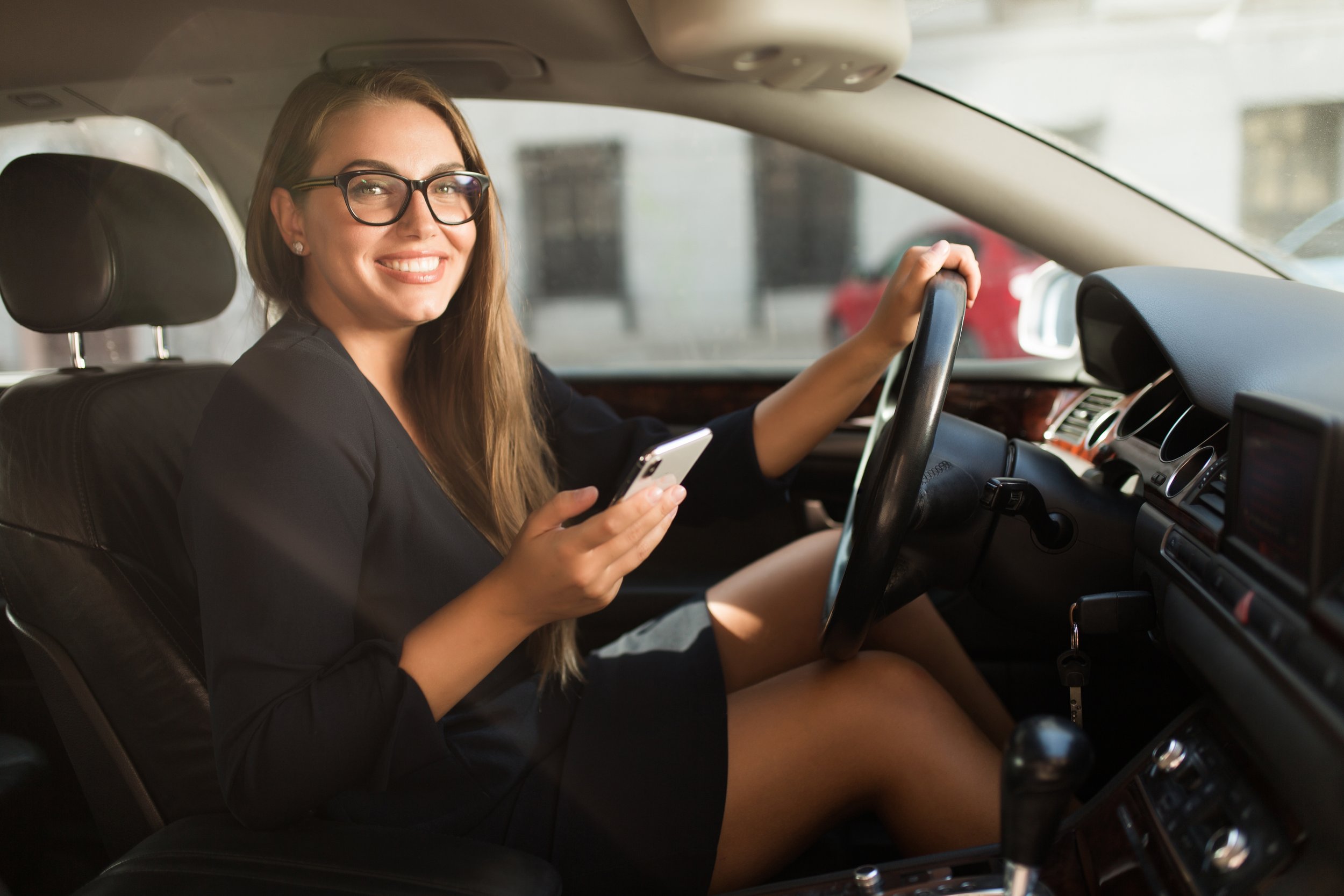 Young cheerful woman in black dress and eyeglasses happily looki